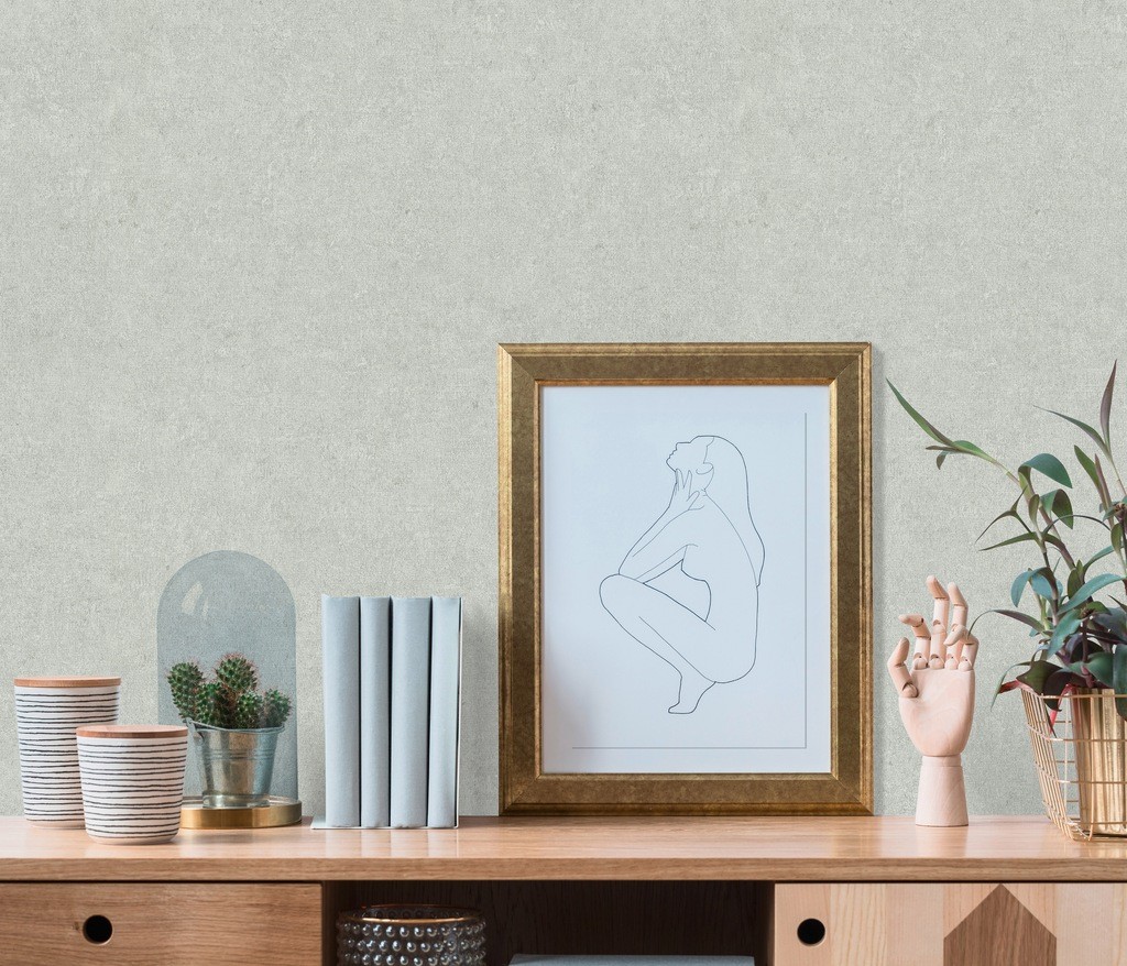 Textured, matte wallpaper in a soft, muted tone, featuring a subtle tonal pattern; displayed alongside a framed line art print, potted plant, and decorative items on a wooden shelf.