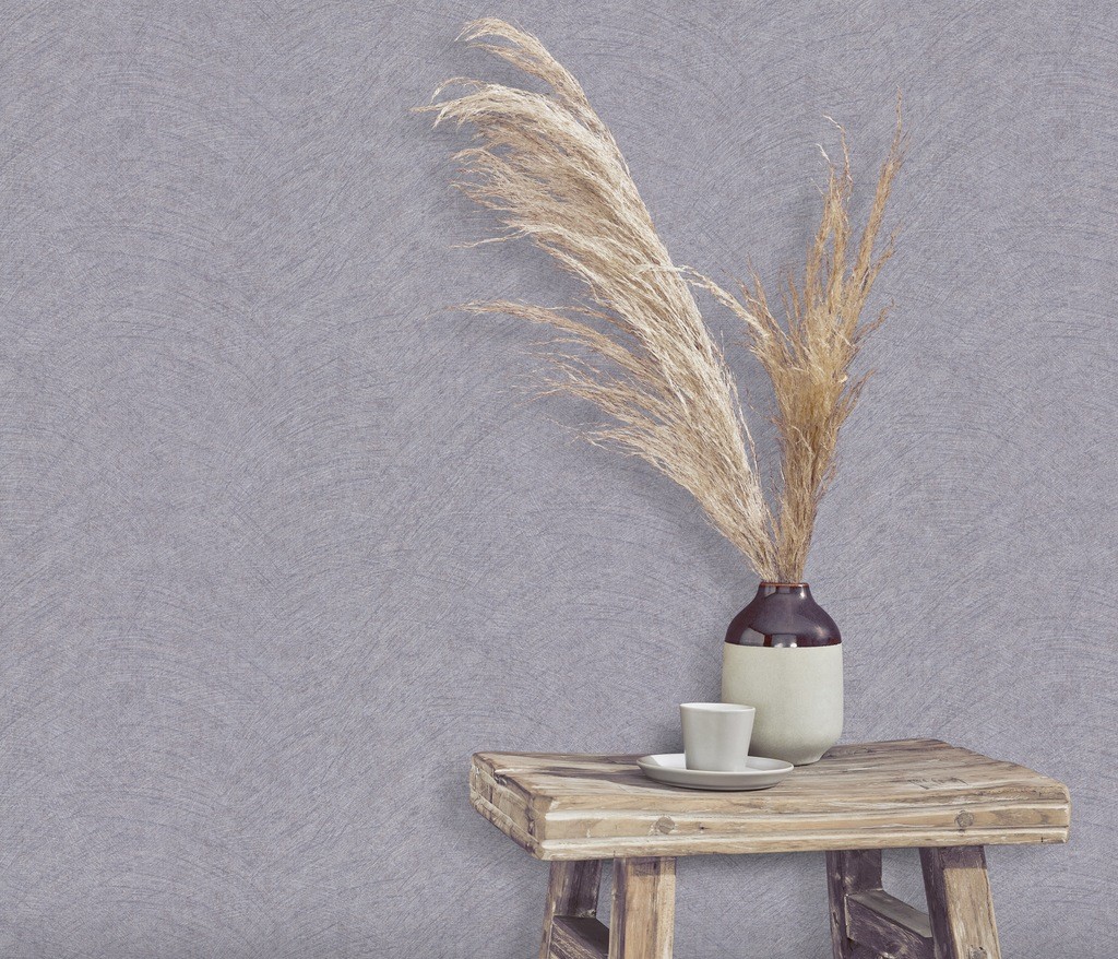 Textured matte wallpaper in a soft gray tone with a subtle pattern, displayed alongside a rustic wooden table, a ceramic vase with dried grass, and a cup on a plate.