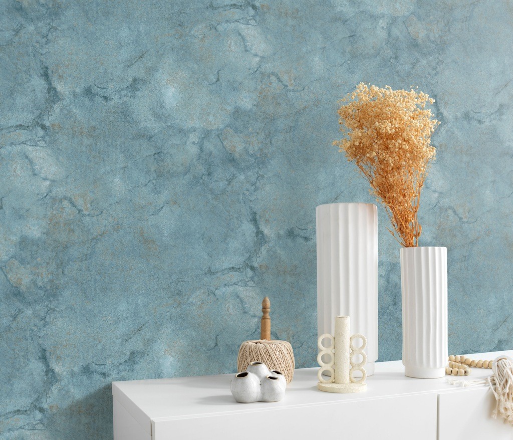 Textured blue wallpaper with a marbled effect, featuring a soft, matte finish, displayed alongside white vases and dried flowers on a light-colored surface.