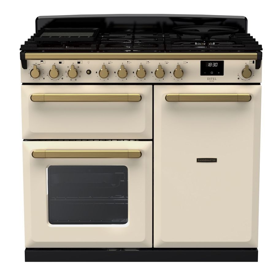 Pale cream dual fuel range cooker with antique brass knobs and handles, featuring five gas burners, two ovens, and a digital clock display.