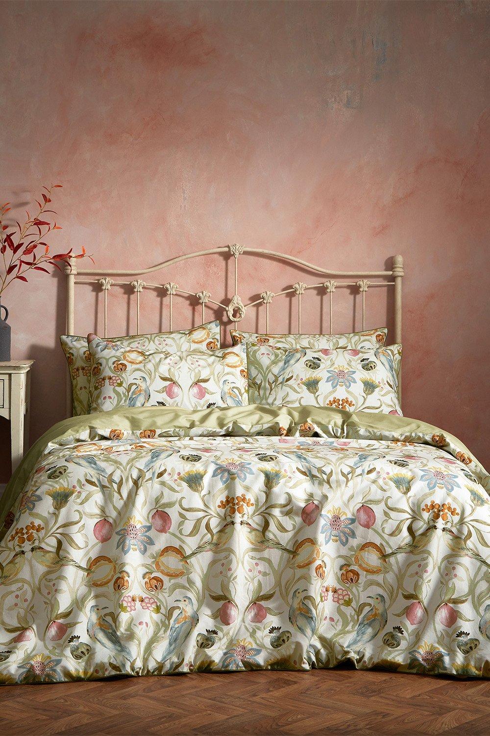 Luxury cotton king duvet cover set featuring a floral design with multi-colored birds on a soft stone background, complemented by matching pillowcases and a vintage-style bed frame.