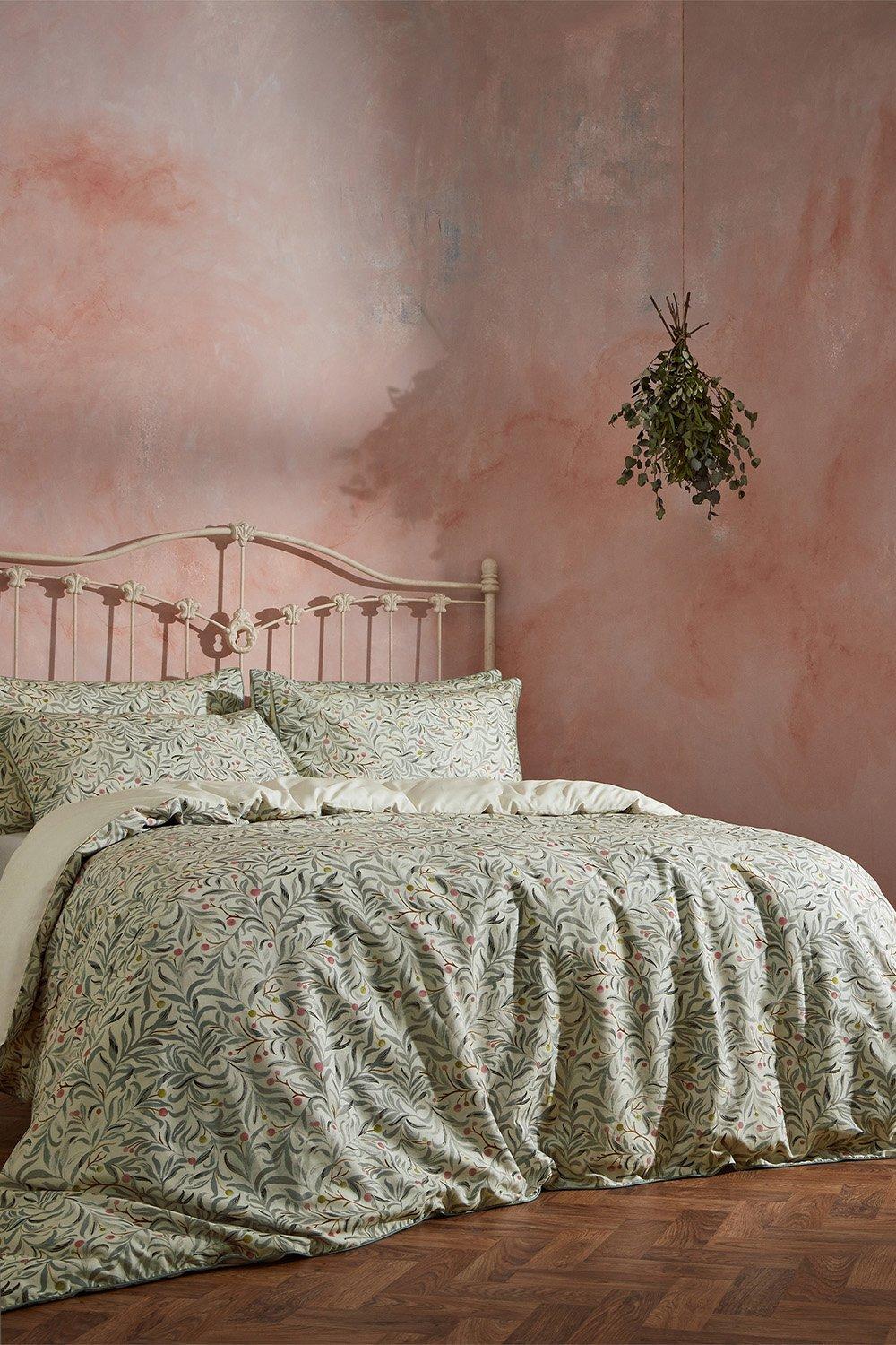 Luxurious green botanical duvet cover set in super king size, featuring intricate floral patterns on soft cotton, complemented by matching pillowcases and a pastel pink wall backdrop.