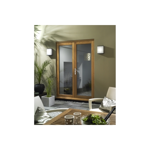 Fully finished oak veneer French doors with a natural wood finish, featuring large glass panels, a sleek handle, and set against a modern outdoor setting with plants and stylish furniture.