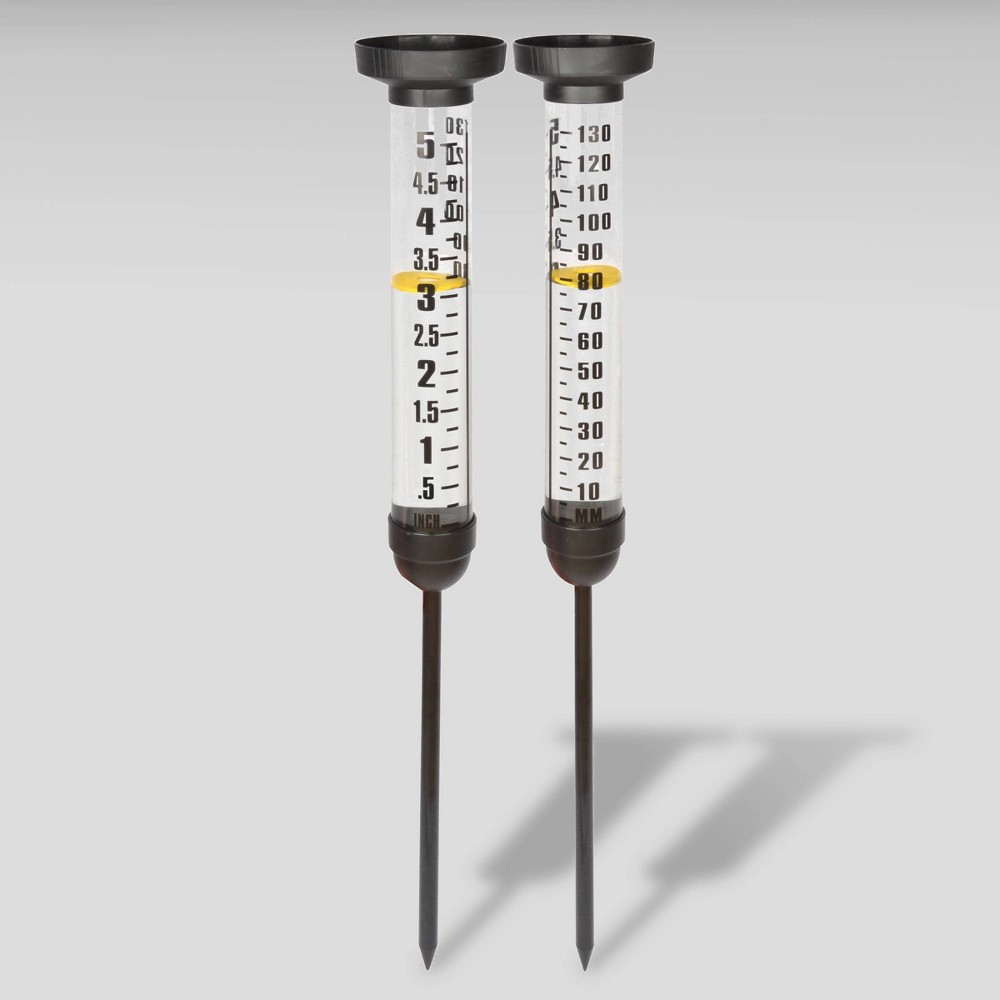 Clear plastic rain gauge with black plastic tops and stakes, marked with measurements in centimeters and inches, featuring a bright yellow indicator at the 3.5 cm level.