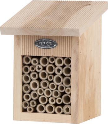 Natural wood bee house with a sloped roof, featuring a front panel filled with various-sized hollow tubes for solitary bees, and a decorative metal label.