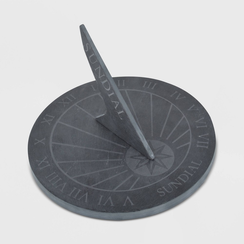 Round blue slate sundial featuring a central gnomon and engraved hour markings, designed for outdoor garden use.