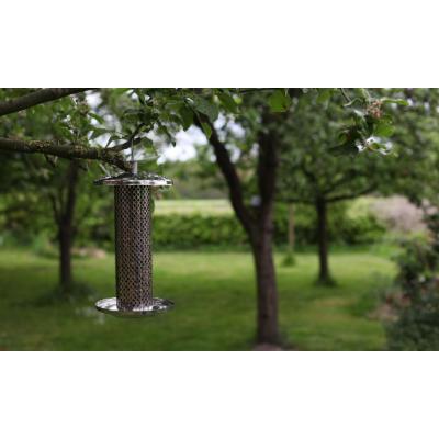 Stainless steel hanging nut feeder in silver, featuring a mesh design for easy access, suspended from a tree branch in a lush green garden setting.