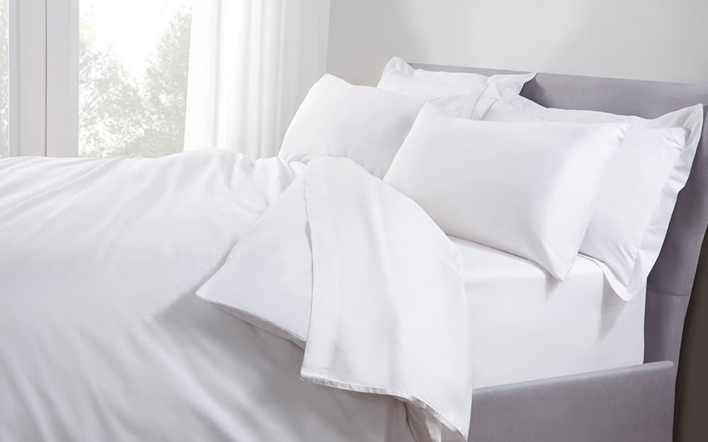 Taupe 250TC cotton percale duvet cover from The Linen Consultancy, featuring a smooth texture, paired with white pillows and a neatly made super king bed.