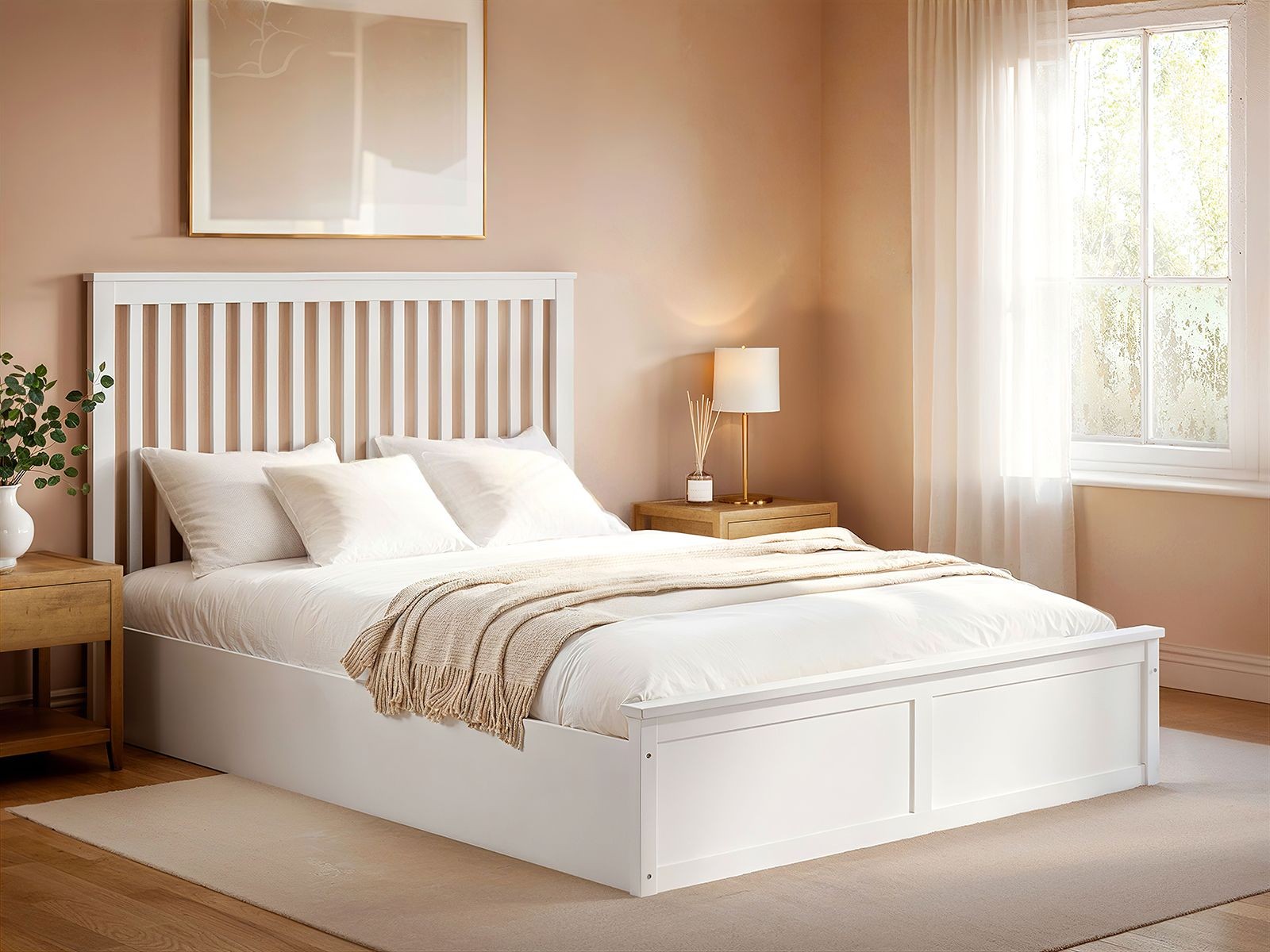 White wooden ottoman bed with a slatted headboard, plush white bedding, and a beige throw, set in a softly lit room with a bedside lamp and a window.