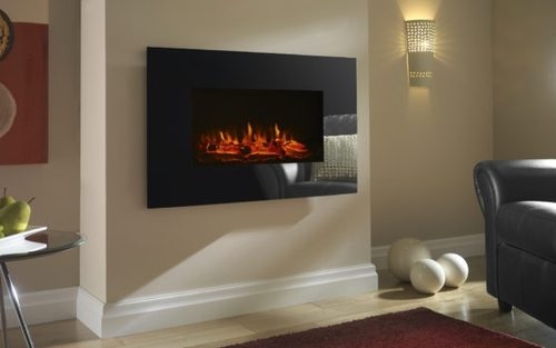 Black glass-effect electric fire mounted on a wall, featuring realistic flame effect, surrounded by a modern living room setting with a dark armchair and decorative elements.