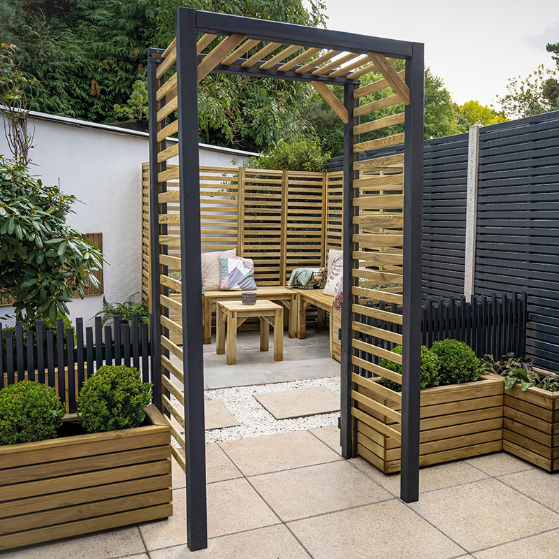 Contemporary slatted garden arch in dark wood with natural slats, measuring 3'8" x 2'5", set in a landscaped area with planters and seating.