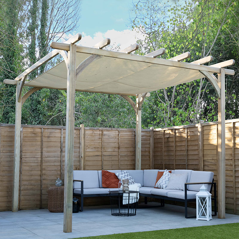 Large wooden pergola in natural wood finish, featuring a retractable beige canopy, set over a grey cushioned seating area with black metal accents and surrounded by a wooden fence.