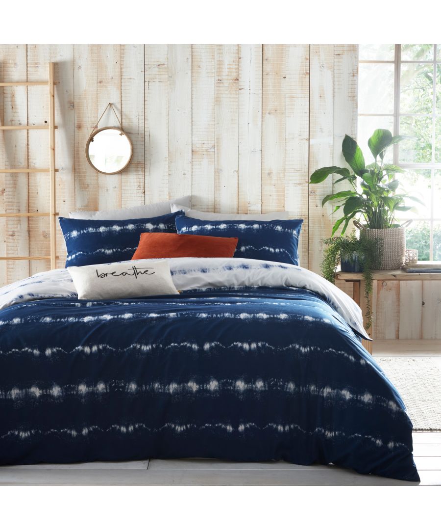 Indigo blue cotton reversible duvet cover set featuring a tie-dye pattern, complemented by two matching pillowcases and a decorative white "breathe" pillow, set against a wooden backdrop.