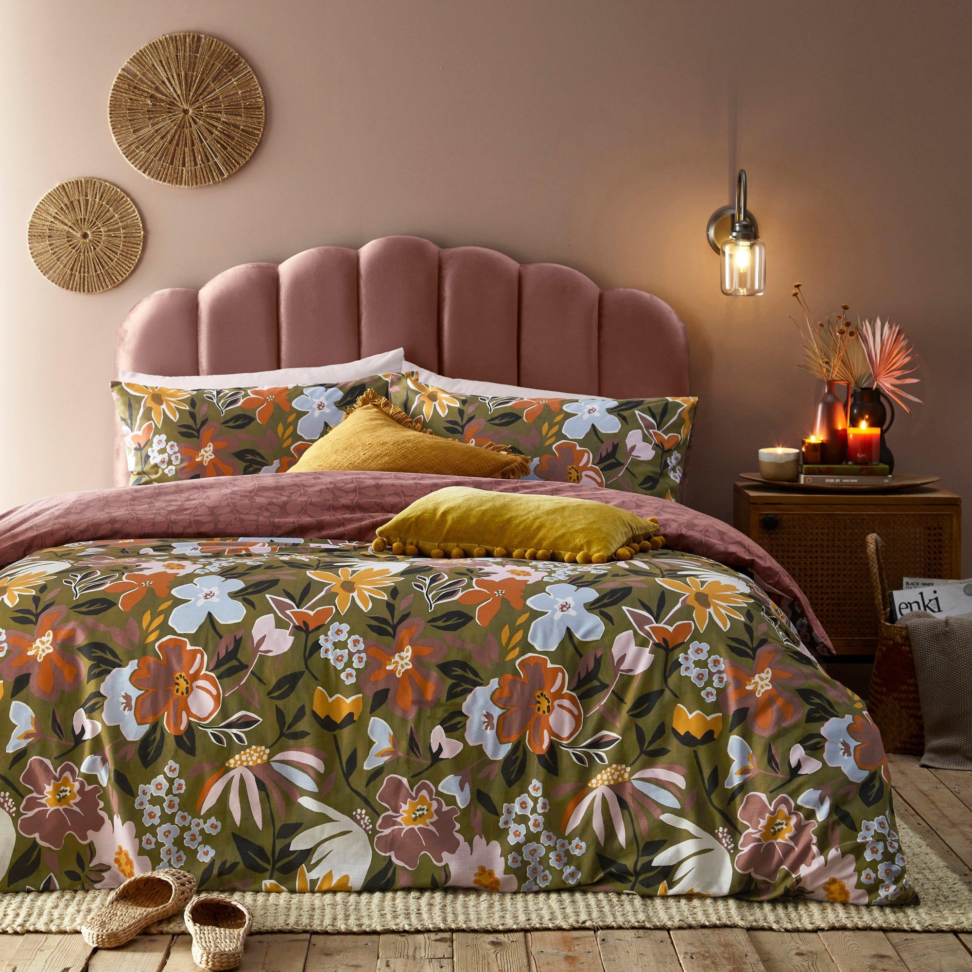 Super King floral duvet cover set in vibrant colors, featuring a mix of flowers on a dark green background, paired with coordinating pillows and textured cushions on a plush bed.