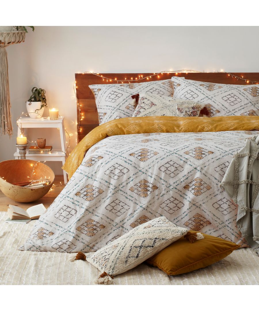 Ochre king-sized duvet cover featuring a geometric pattern in warm tones, complemented by textured pillows and soft throws, set in a cozy, softly lit bedroom.