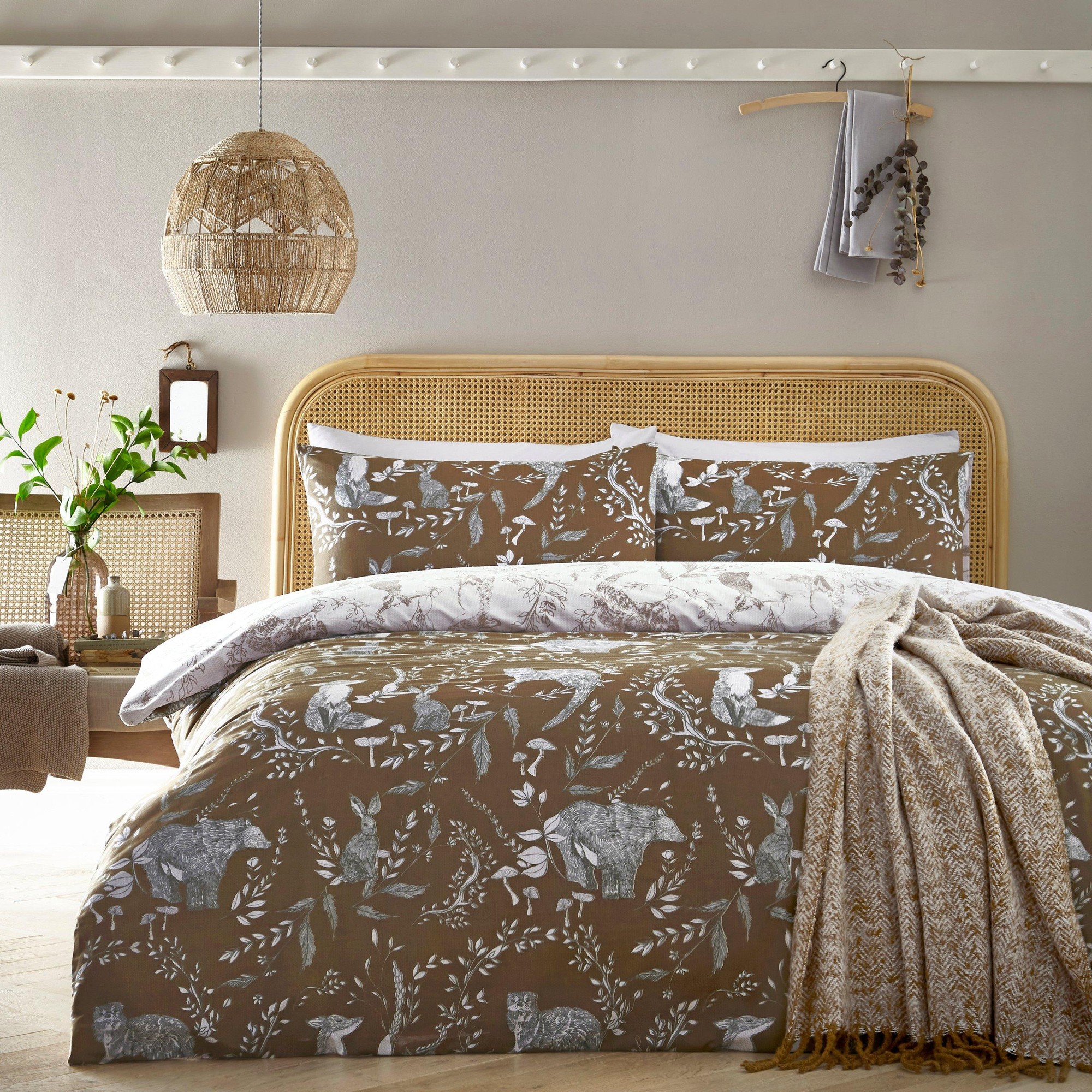 Buckthorn Duvet Cover Set in orange features a nature-inspired print with animals and foliage, complemented by matching pillowcases and a soft, textured material.