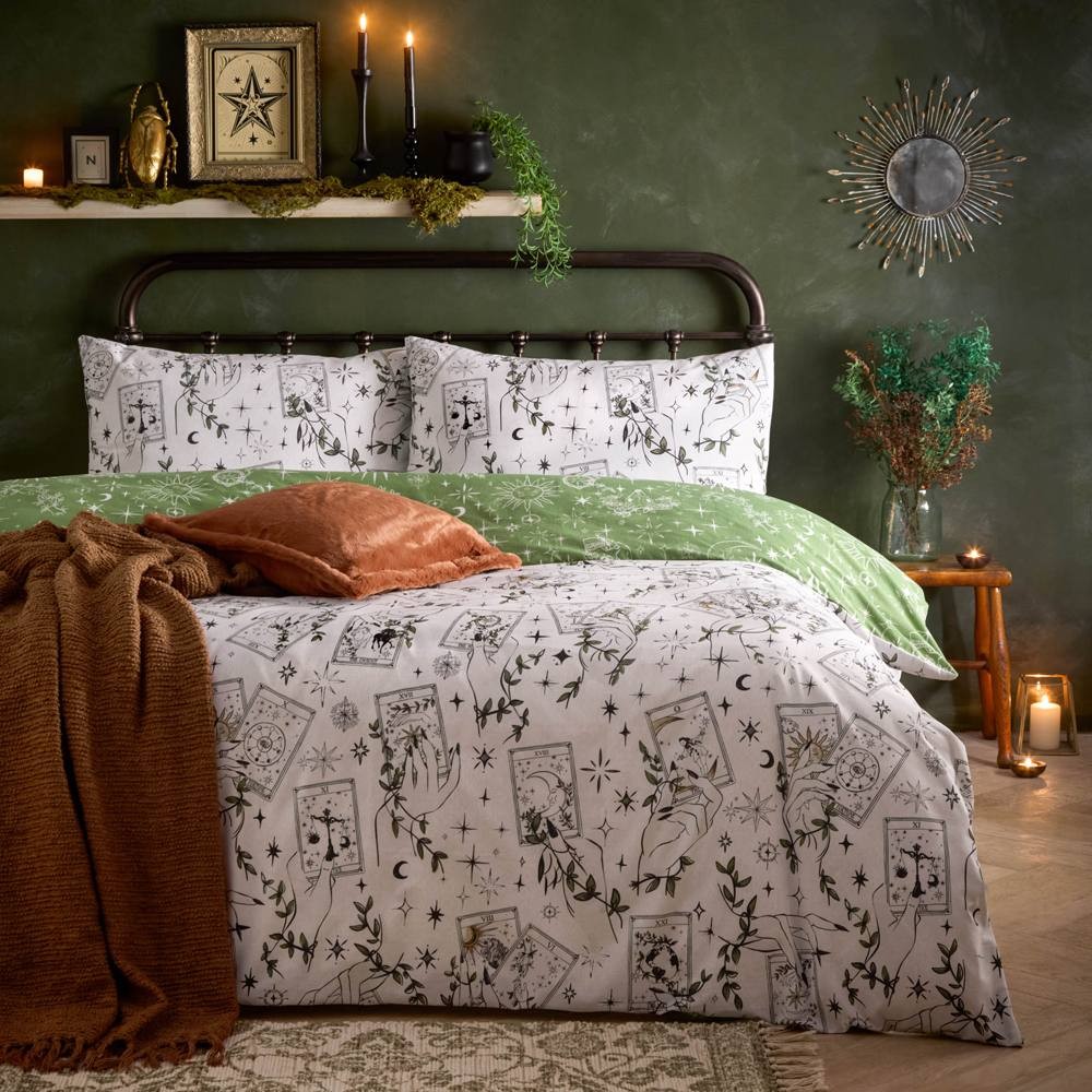 Reversible duvet cover set in green and white, featuring celestial-themed prints, paired with matching pillowcases and a textured brown throw, styled in a cozy bedroom setting.