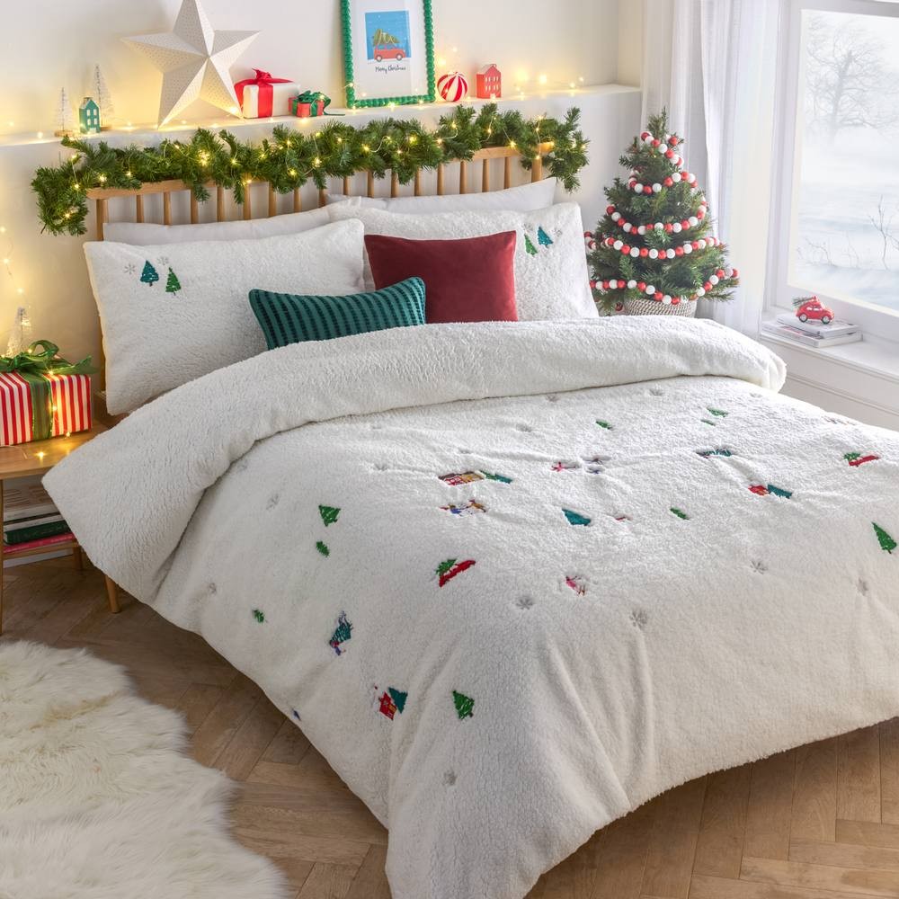 White teddy fleece duvet cover set featuring festive embroidered Christmas trees and decorations, complemented by matching pillowcases and a cozy bedroom setting with holiday decor.