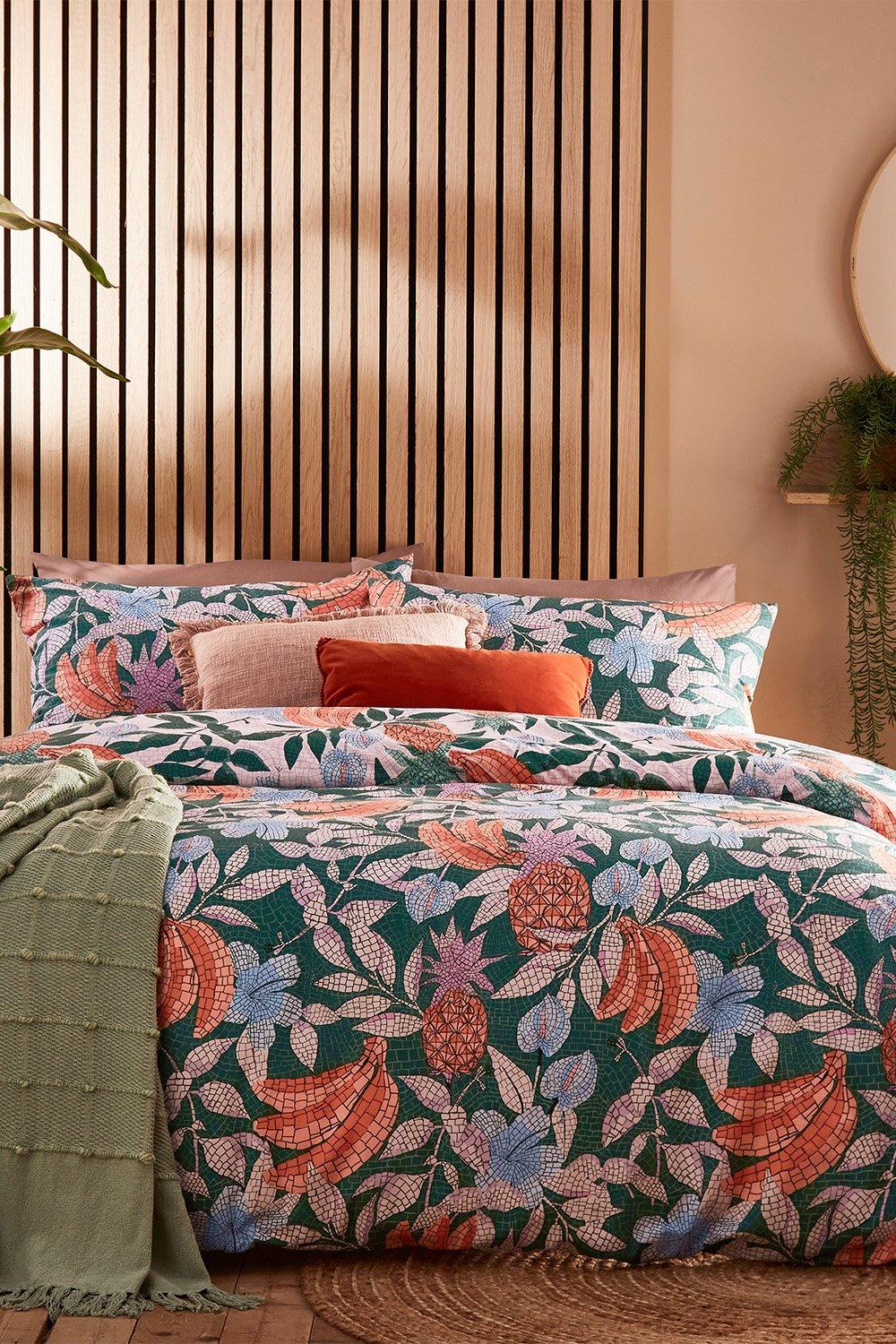 Cypressa Mosaic reversible duvet cover set in green polycotton features vibrant floral patterns, complemented by decorative pillows and a textured green throw, suitable for a super king bed.