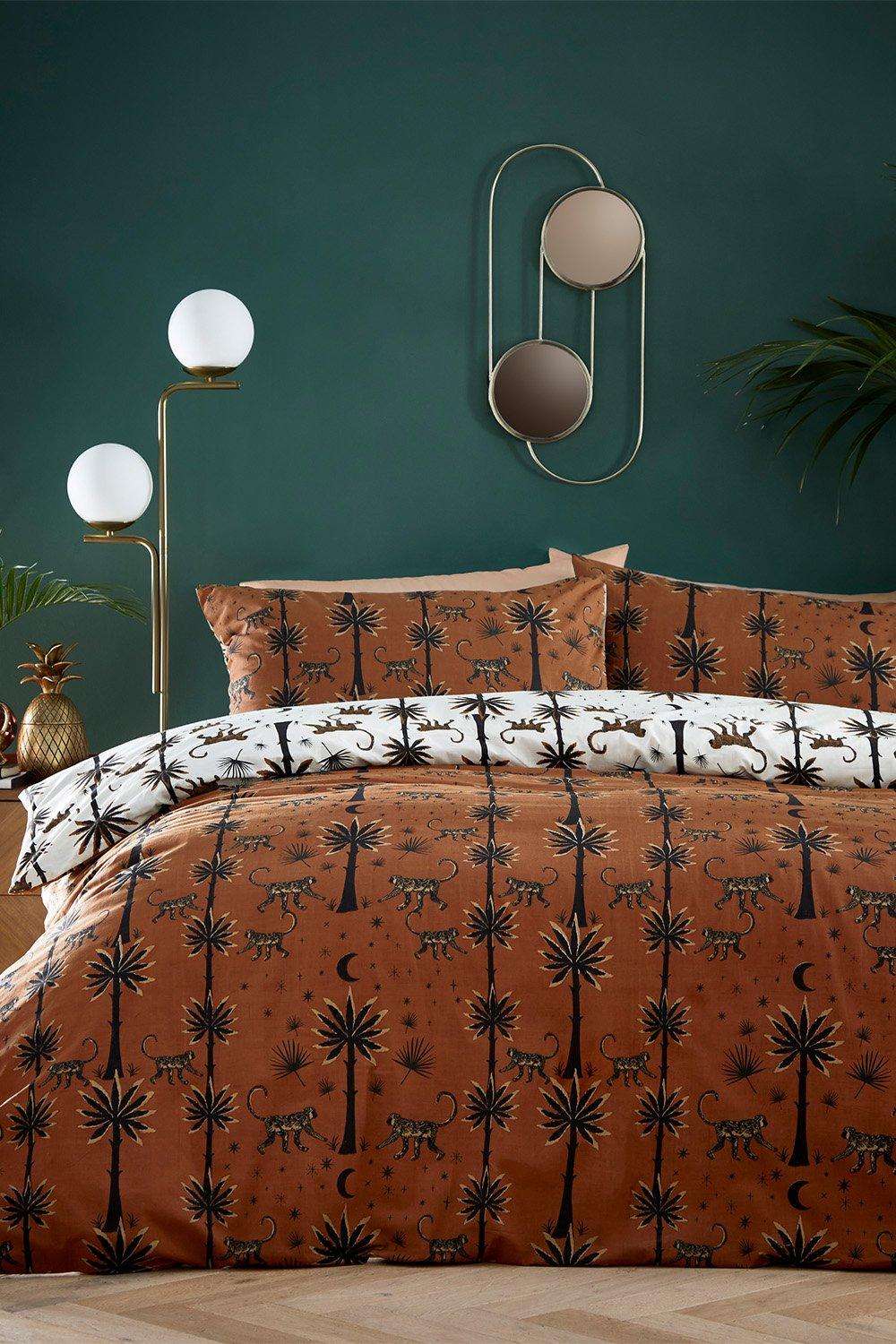 Brown polycotton duvet cover set featuring exotic desert monkey and palm tree patterns, complemented by white pillowcases, styled against a dark green wall with modern decor.