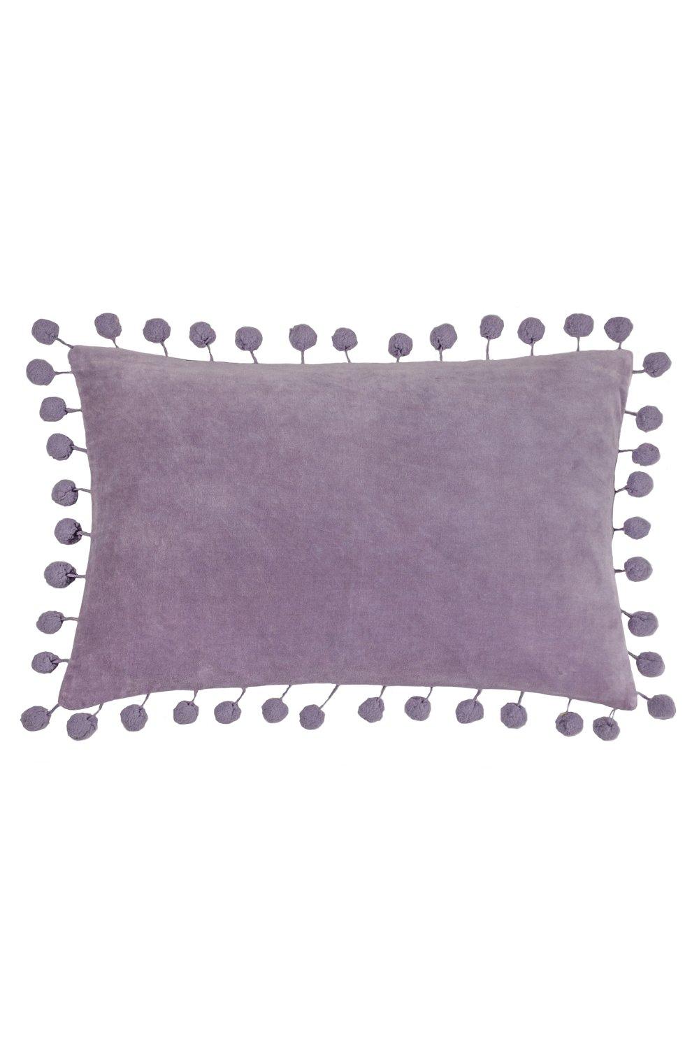 Rectangular lilac cushion made of soft velvet, featuring a plush polyester filling and adorned with playful pom pom trim along the edges, measuring 30cm x 50cm.