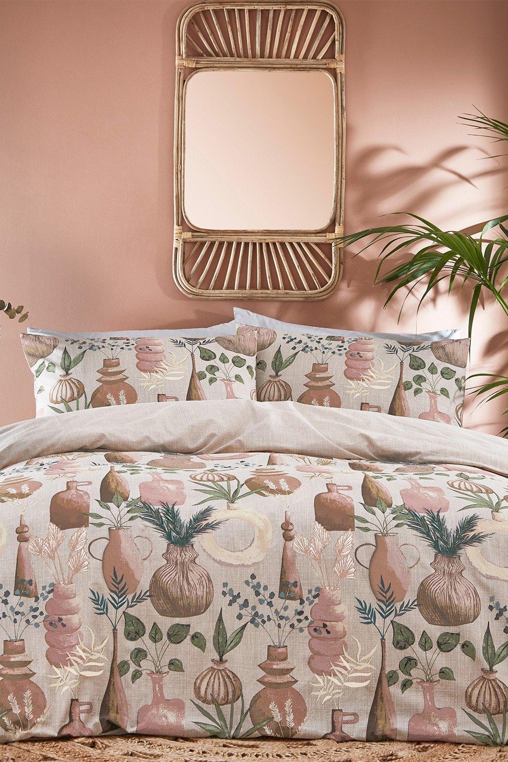 Beige polycotton duvet cover set featuring a botanical print with vases and foliage, complemented by matching pillowcases, displayed against a pink wall and a rattan mirror.