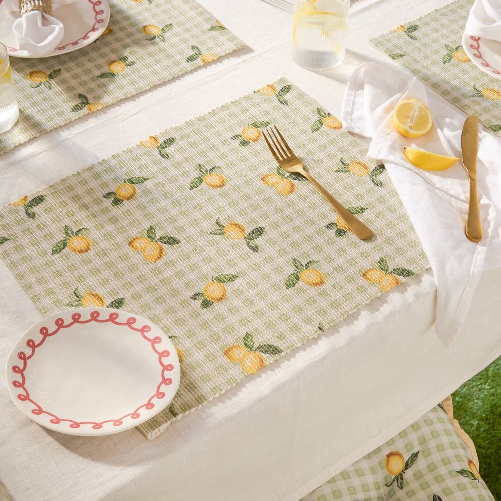 Set of four yellow indoor/outdoor placemats featuring a lemon pattern on a green checkered background, made of durable fabric, perfect for casual dining.