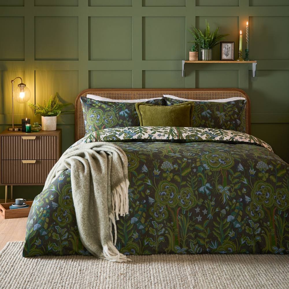 Reversible duvet cover set in green featuring a floral design, complemented by matching pillowcases, a cozy throw, and a stylish bed frame against a green paneled wall.
