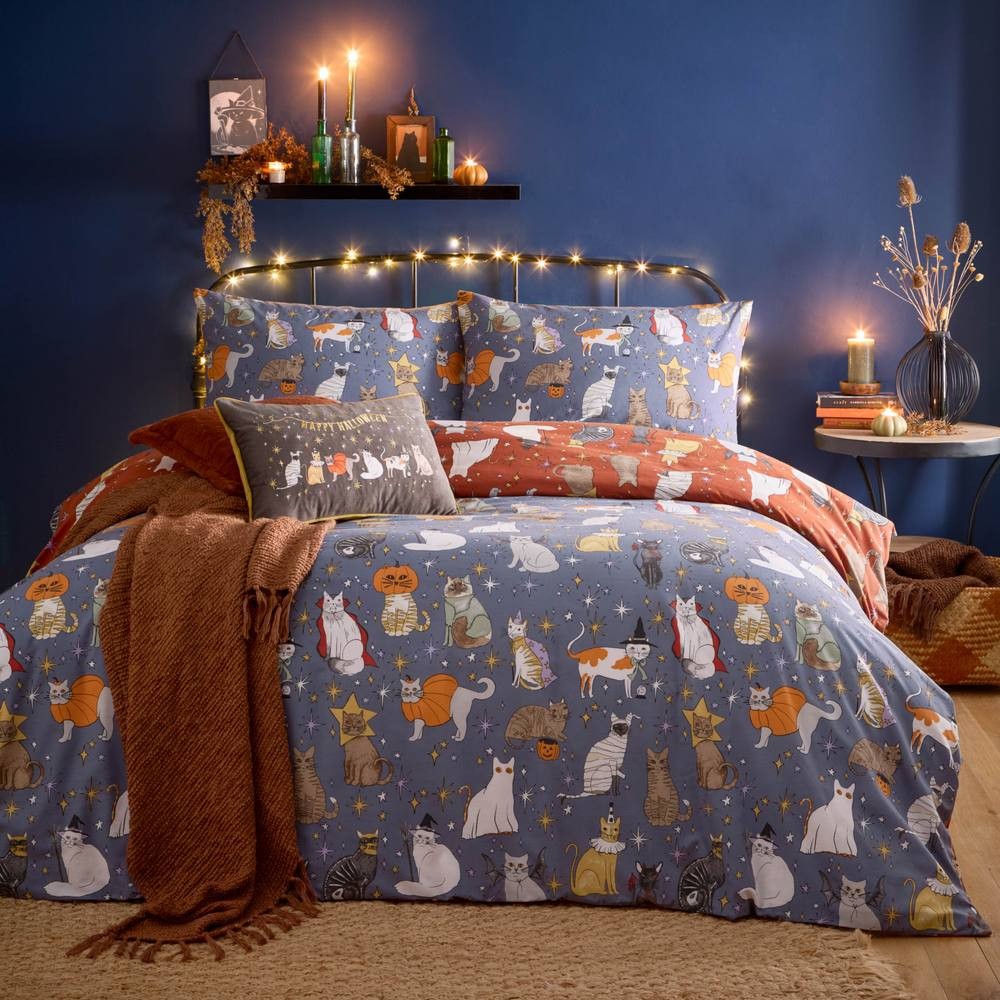 Reversible king duvet set featuring playful Halloween-themed cat illustrations in vibrant colors, with one side in orange and the other in a blue pattern, complemented by cozy accessories.