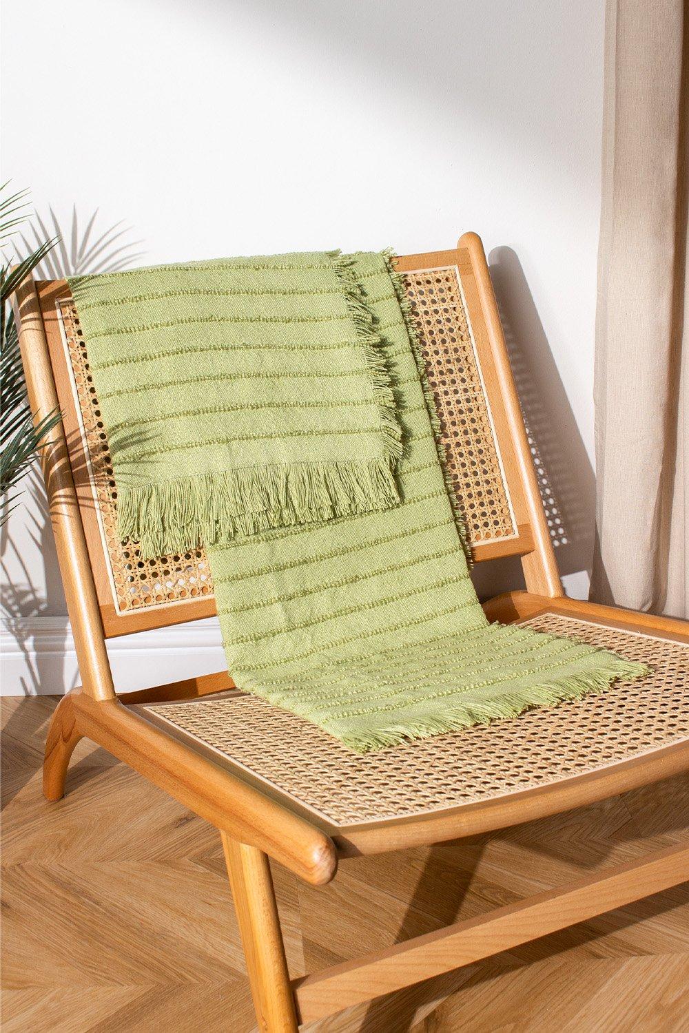 Green yarn-woven throw with fringed edges draped over a wooden chair, featuring a textured striped pattern, ideal for cozy decor.