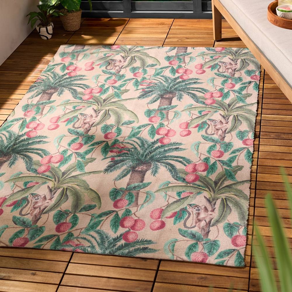 Tropical indoor/outdoor rug featuring vibrant palm trees, monkeys, and cherries in green, pink, and beige hues, made from durable material, perfect for adding a lively touch to any space.