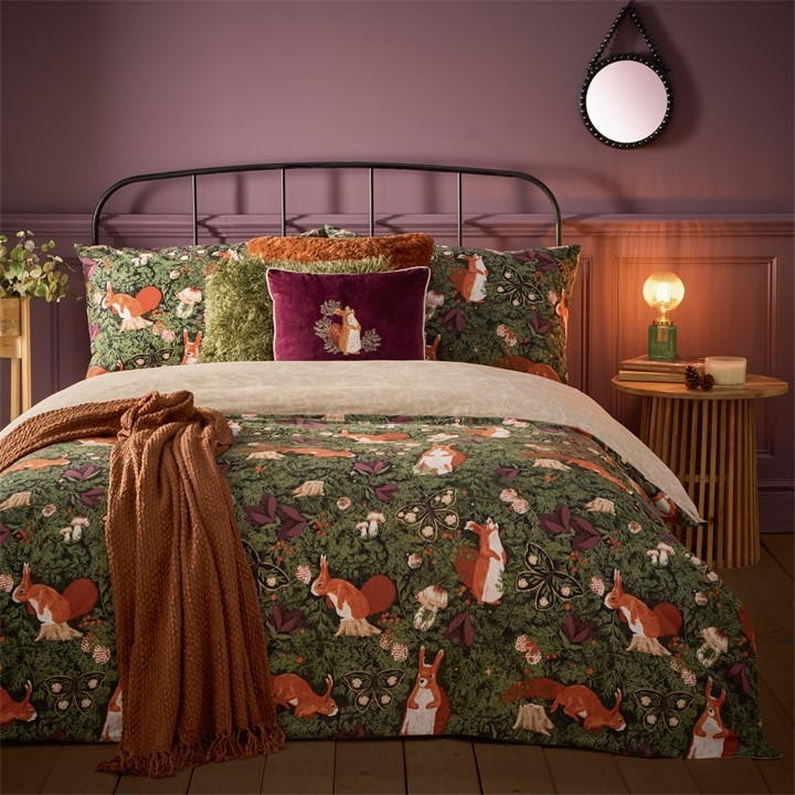 Multicoloured Pineberry Forest Woodland duvet cover set featuring whimsical fox and rabbit patterns on a dark green background, complemented by a plush purple cushion and cozy throw.