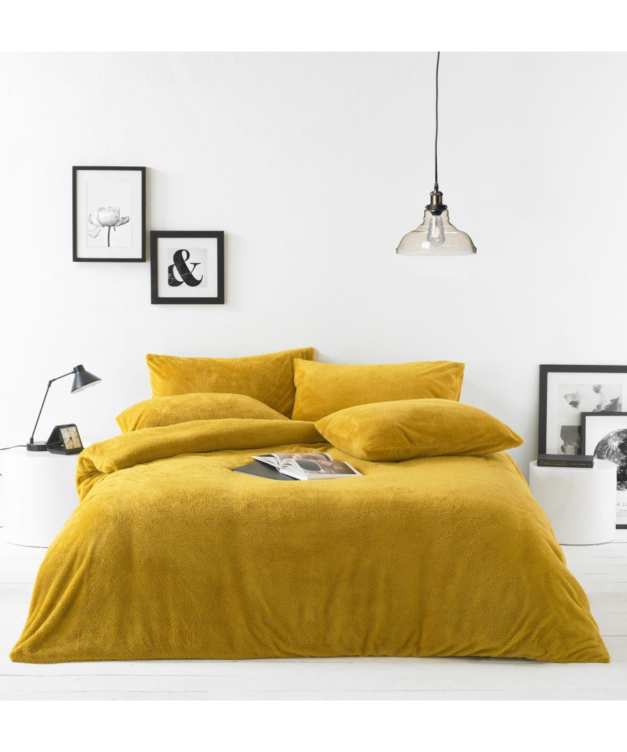 Soft ochre yellow sherpa duvet set for a double bed, featuring plush texture and matching pillows, styled with minimalist decor and framed artwork in the background.