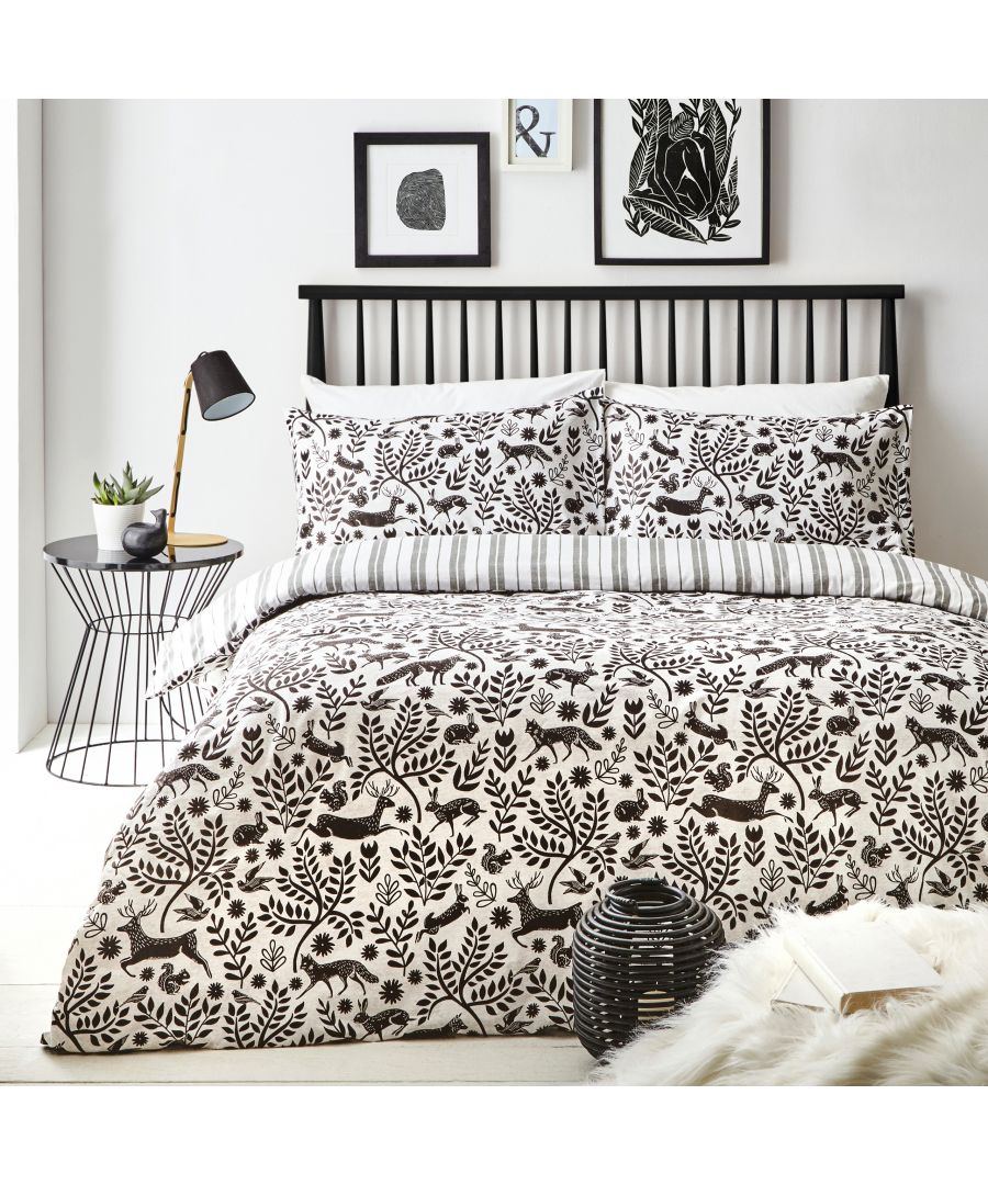 Minimalist charcoal reversible duvet cover set featuring woodland patterns, complemented by striped pillowcases, styled in a modern bedroom with black and white decor.