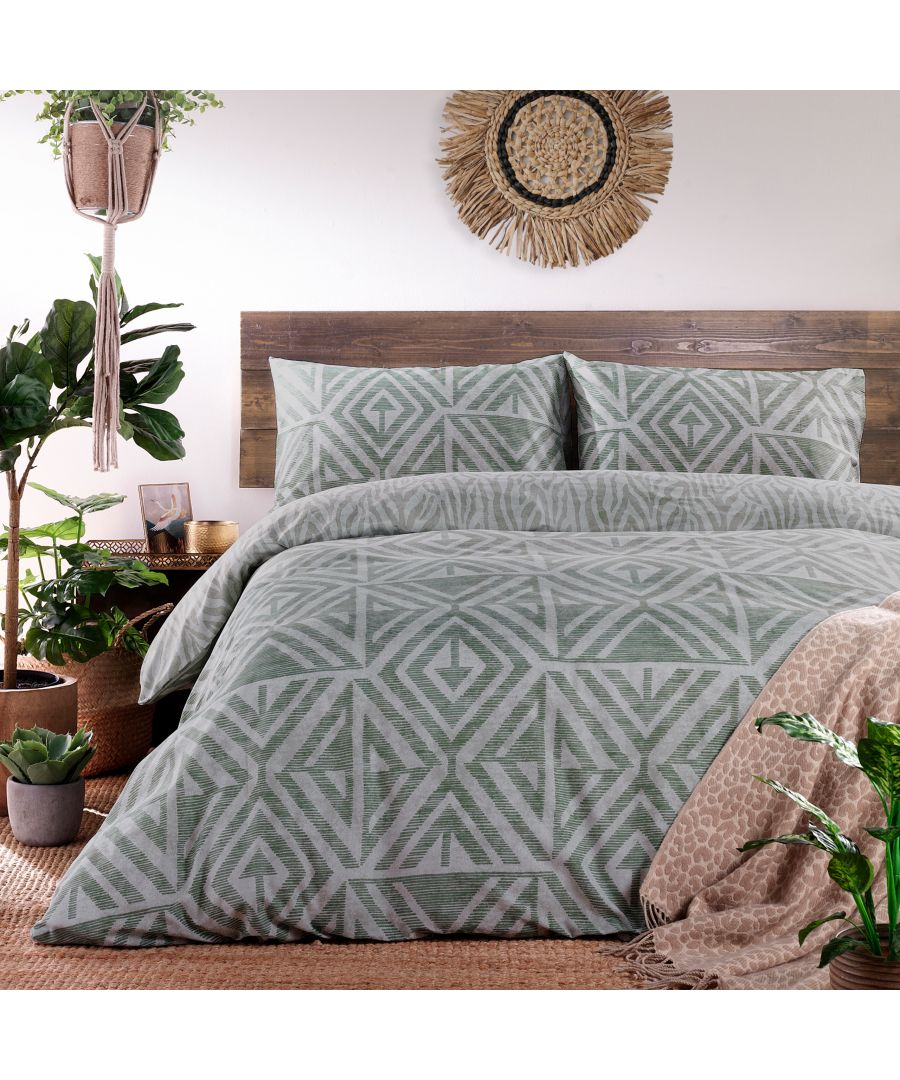 Green geometric patterned bedding set with matching pillowcases, displayed on a wooden bed frame, surrounded by indoor plants and natural decor elements.