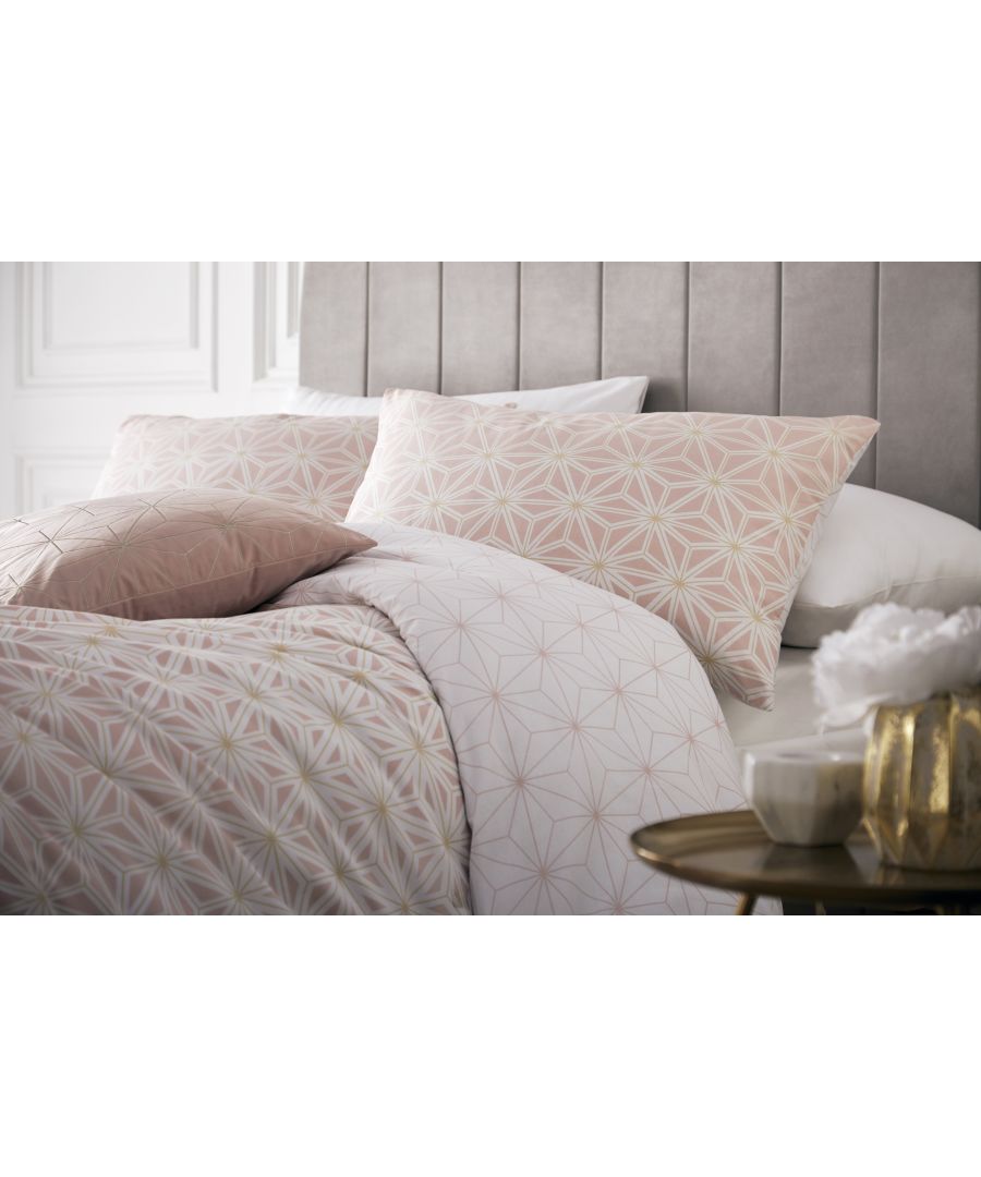 Pink cotton duvet set featuring a geometric tessellated pattern in blush and gold, complemented by matching pillowcases, styled on a bed with a gray headboard and decorative accessories.