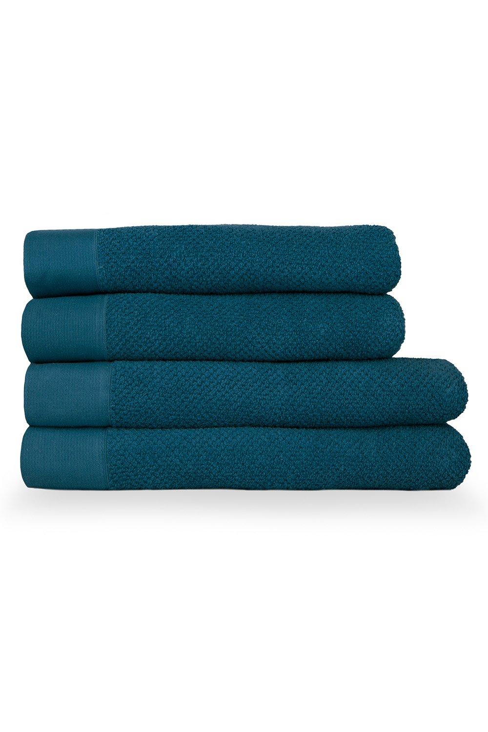 Four stacked bath towels in a rich teal color, featuring a textured weave and smooth cotton panels, showcasing a soft, plush appearance ideal for bathroom use.