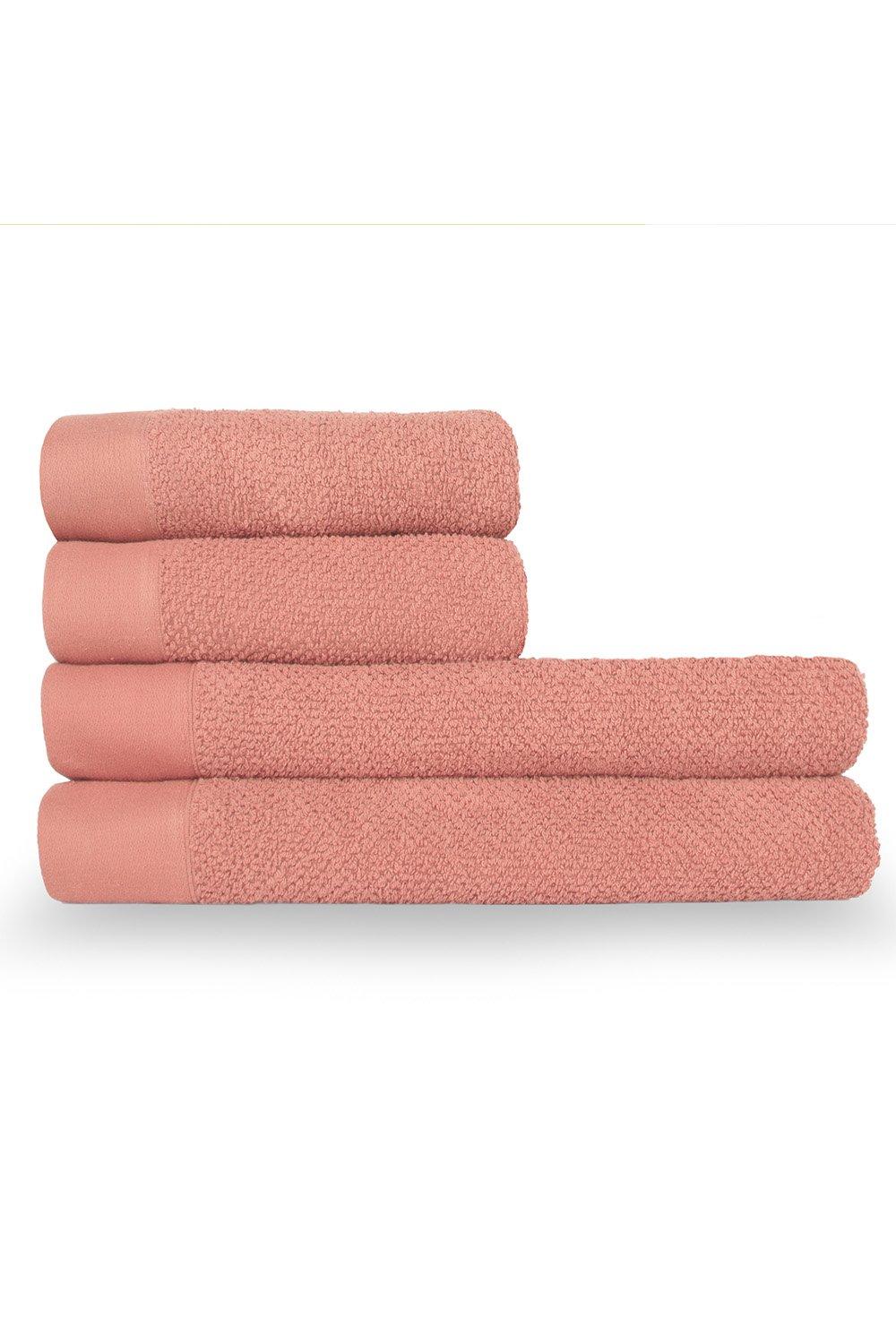 Four soft, textured weave cotton towels in a warm peach color, featuring a smooth border and plush terry fabric, neatly stacked.