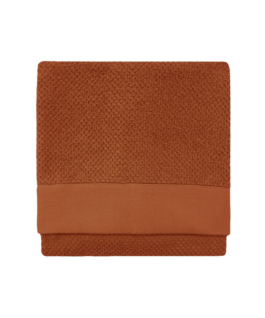 Textured brown cotton hand towel with a woven design and a smooth, solid-colored band at the bottom, folded neatly in a square shape.
