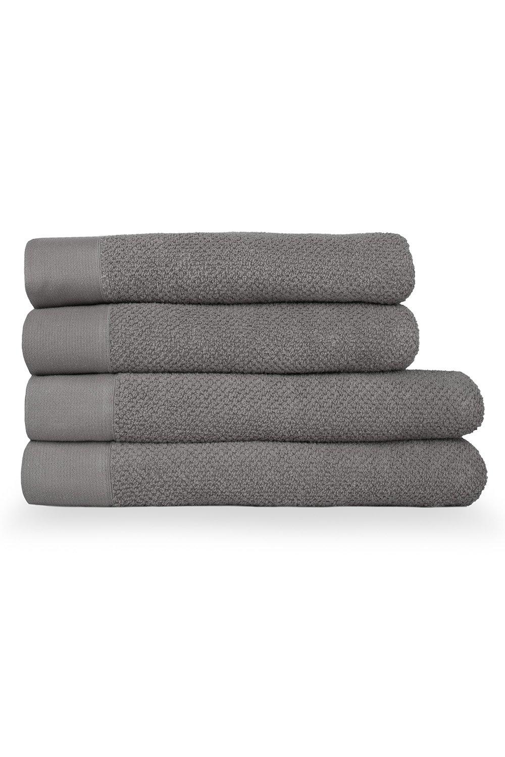 Four stacked bath towels in a soft gray color, featuring a textured weave and smooth cotton panel, showcasing a luxurious and absorbent design.