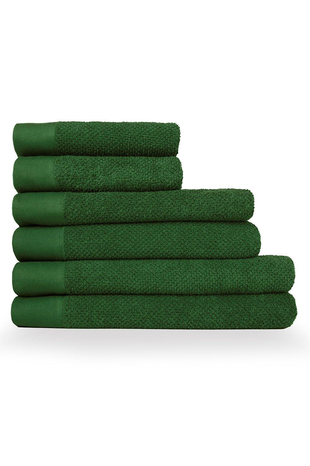 Six-piece towel set in a rich green color featuring a textured weave and cotton material, including hand towels, bath towels, and sheets neatly stacked.