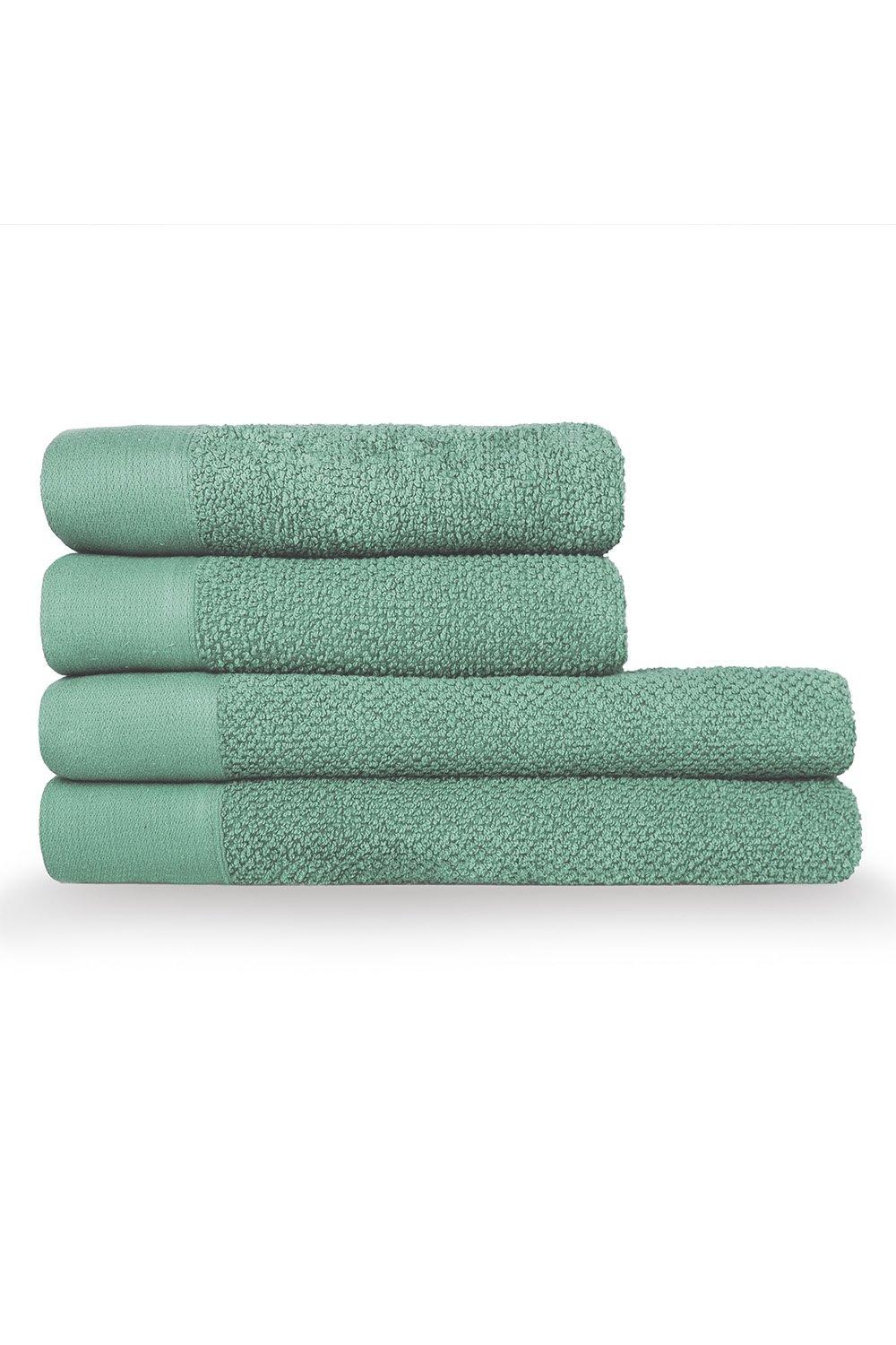 Four stacked towels in a soft green color, featuring a textured weave design with a smooth cotton finish, ideal for hand and bath use.