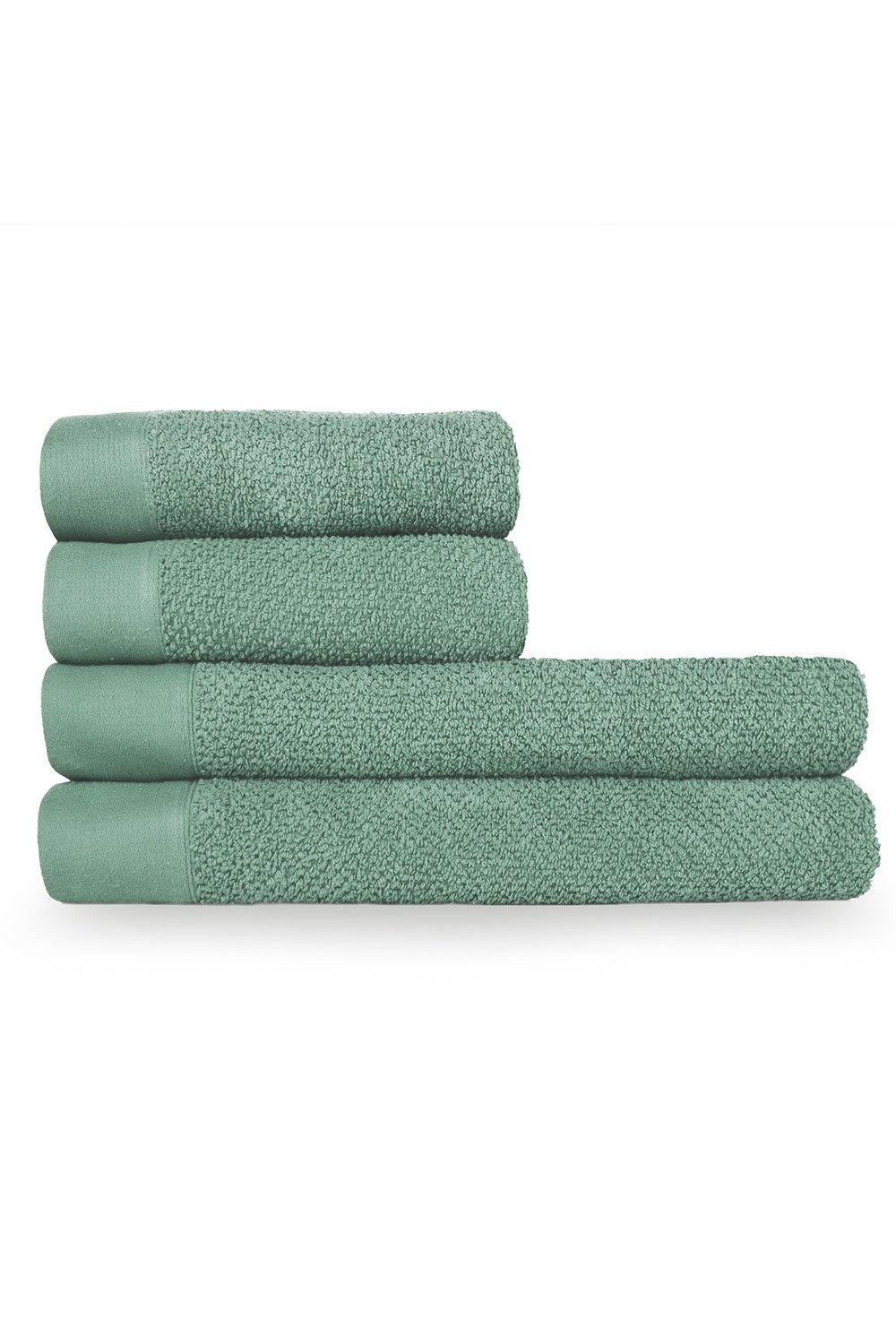 Four stacked towels in a soft green hue, featuring a textured weave and smooth cotton panel, ideal for hand or bath use.