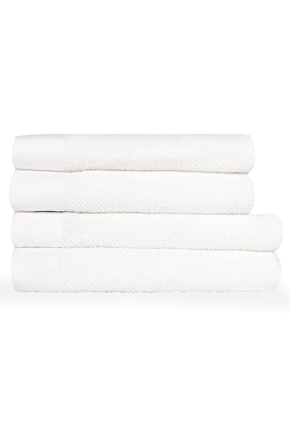Four neatly stacked white cotton bath towels featuring a textured weave and panel design, ideal for a luxurious bathroom experience.