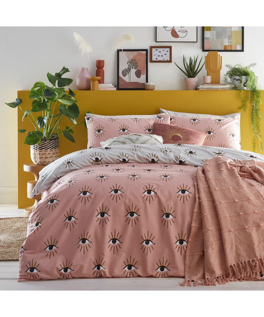 Blush cotton duvet cover set featuring an abstract eye design, complemented by matching pillowcases, styled with a textured throw and vibrant decor against a yellow headboard.