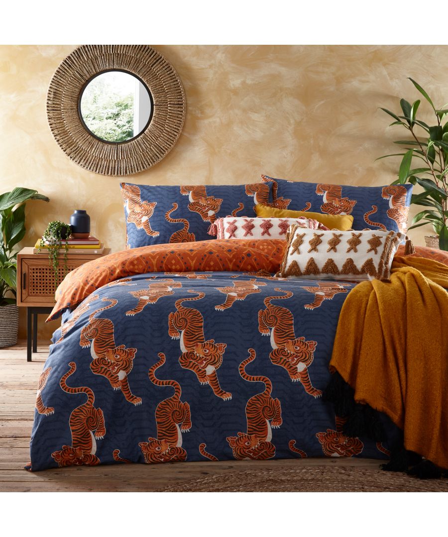 Reversible duvet cover set featuring blue cotton with vibrant orange Tibetan tiger tribal patterns, complemented by decorative pillows and a cozy mustard throw.