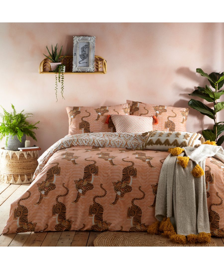 Orange cotton duvet cover set featuring Tibetan tiger patterns, complemented by matching pillowcases, a textured throw, and decorative cushions against a soft pink backdrop.
