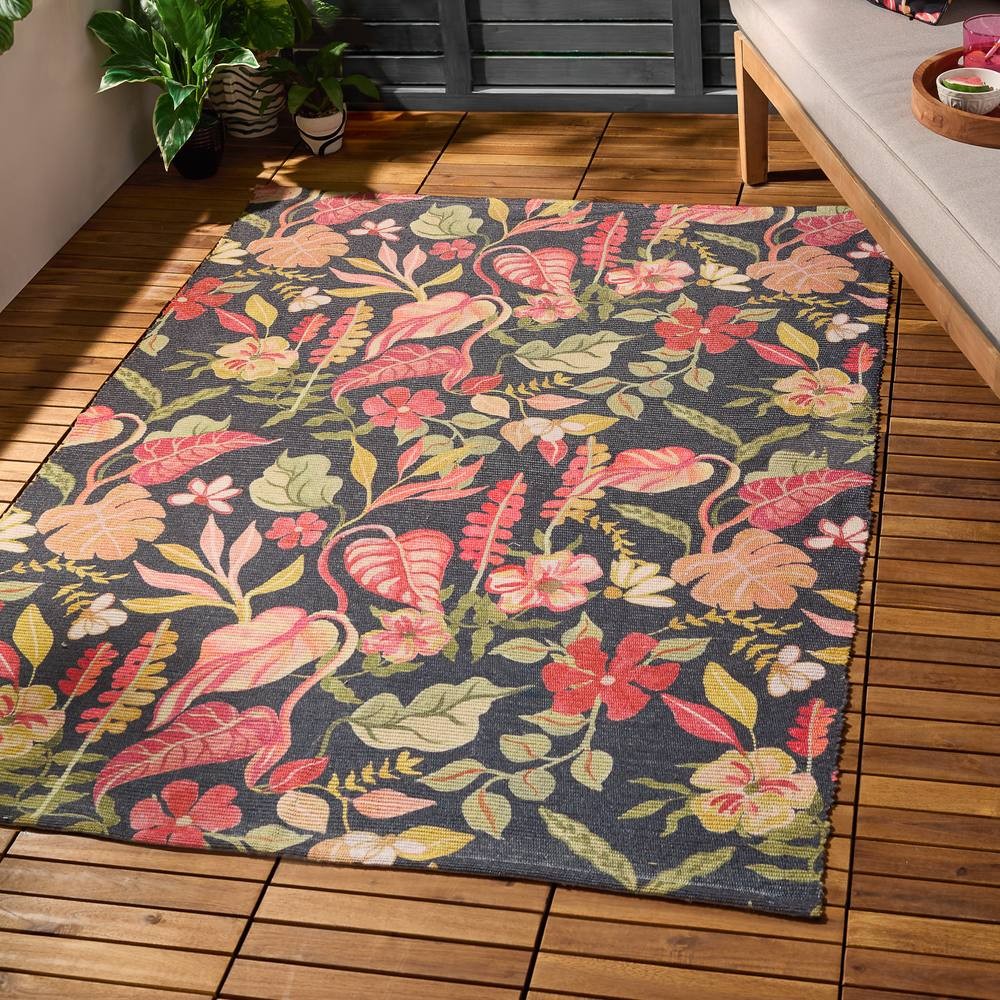 Tropical floral rug featuring vibrant pink and green patterns on a black background, suitable for indoor or outdoor use, with a textured weave and bordered edges.