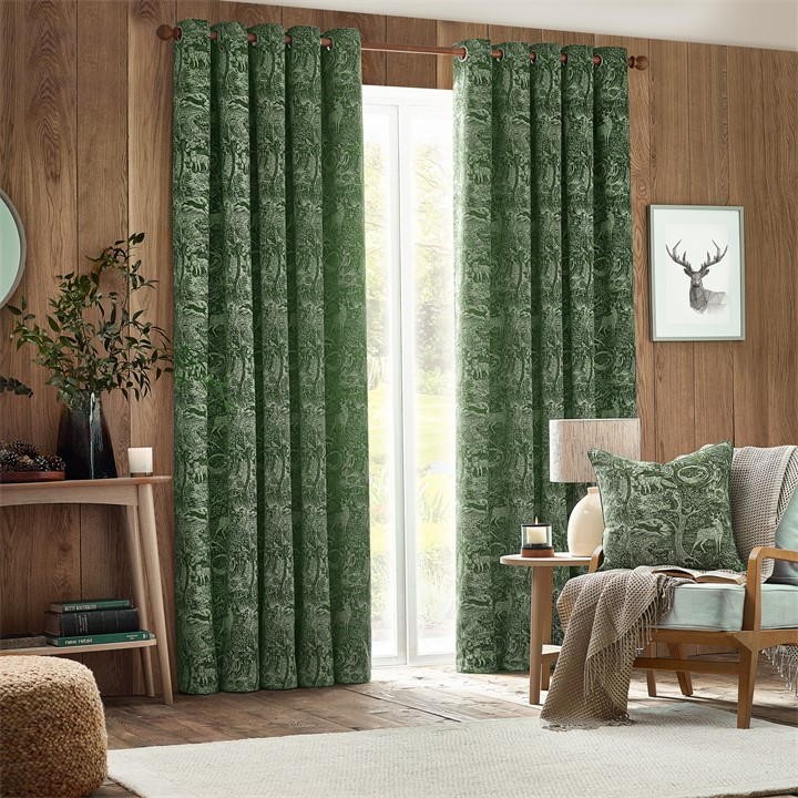 Emerald green chenille eyelet curtains featuring a winter woods animal pattern, measuring 117cm width by 137cm drop, elegantly framing a bright window in a cozy room.