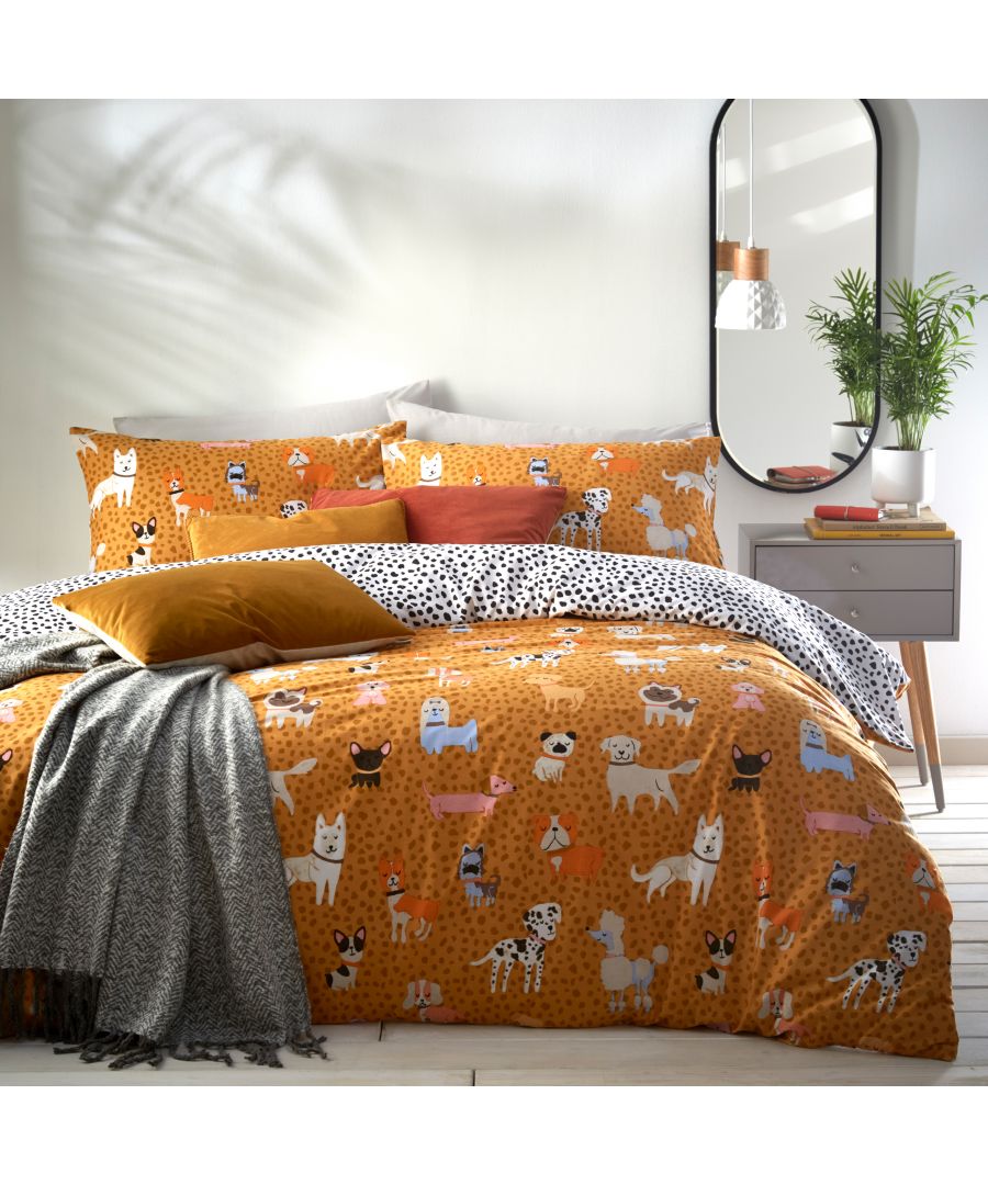Bright orange duvet set featuring playful dog illustrations, complemented by a black and white polka dot pattern on the pillowcases, with a cozy gray throw draped over the bed.